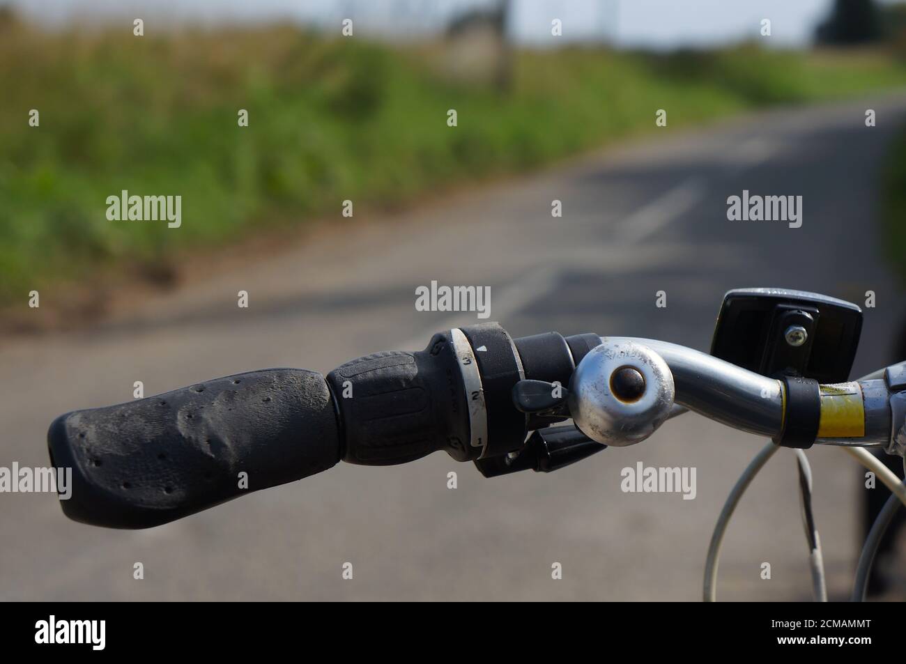 Primo piano del manubrio della bicicletta con una strada morbida che si snoda davanti Foto Stock