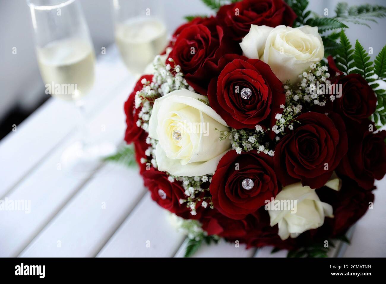 Bel bouquet di nozze di rose rosse e bianche vellutate su un tavolo con due  flute di champagne da parte, concetto di matrimonio o il bouquet della sposa  Foto stock - Alamy