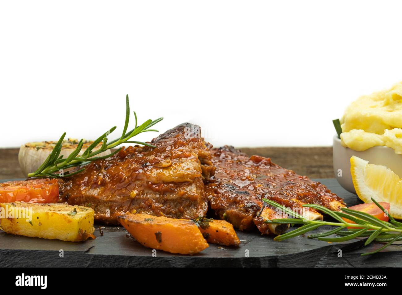 Costolette di maiale arrosto con purè di patate e pomodori arrosto su sfondo bianco. Foto Stock