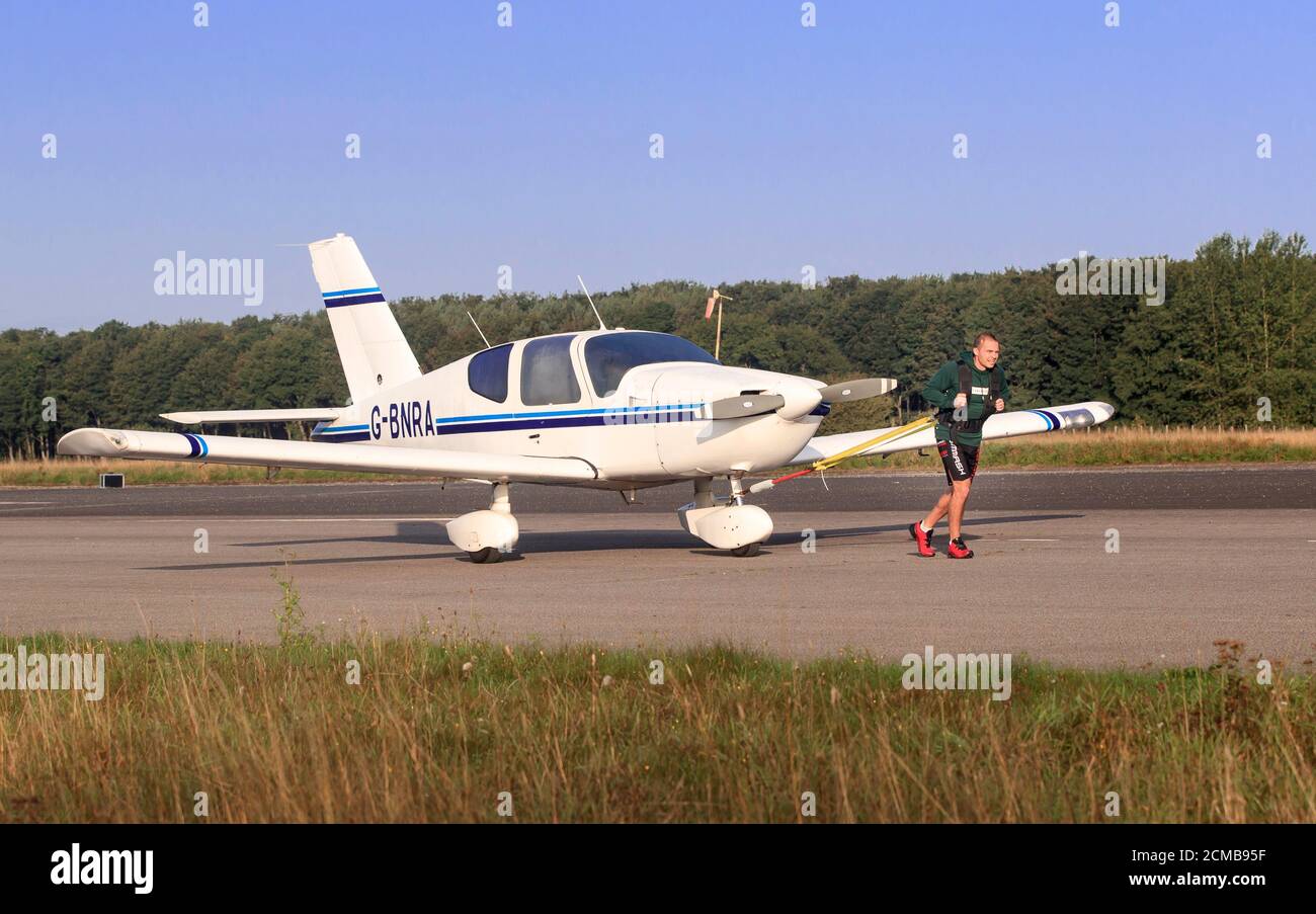 Il campione del kickboxing mondiale Carl Thomas durante il suo tentativo di correre una maratona mentre tira un aereo a Elvington Airfield vicino York. Foto Stock