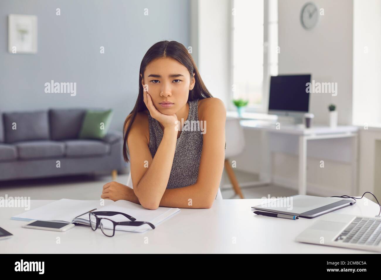 Triste ragazza asiatica esaurisce le idee e soffre da crisi creativa incapace di scrivere un buon saggio Foto Stock