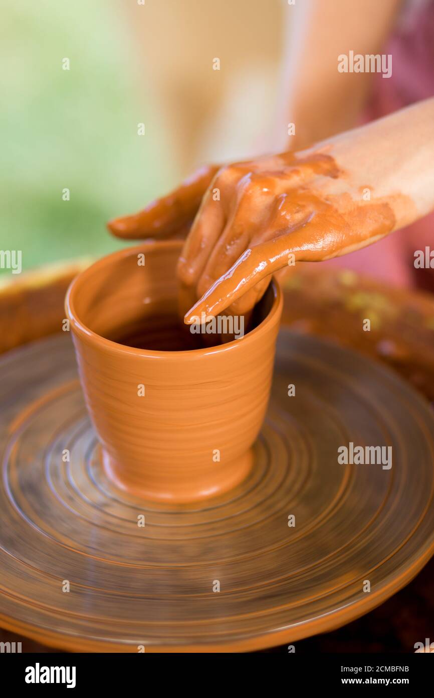 Le mani della donna scolpisce la tazza dal vaso di creta. Laboratorio di modellazione su ruota di vasaio. Foto Stock