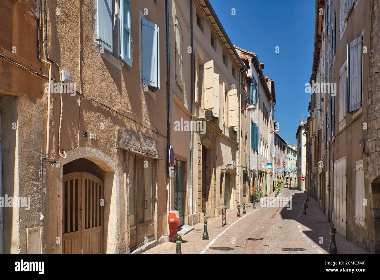 Una strada laterale illuminata dal sole che mostra i classici vecchi vani porta, le finestre e le persiane nella vecchia città di Millau, Aveyron, Francia Foto Stock
