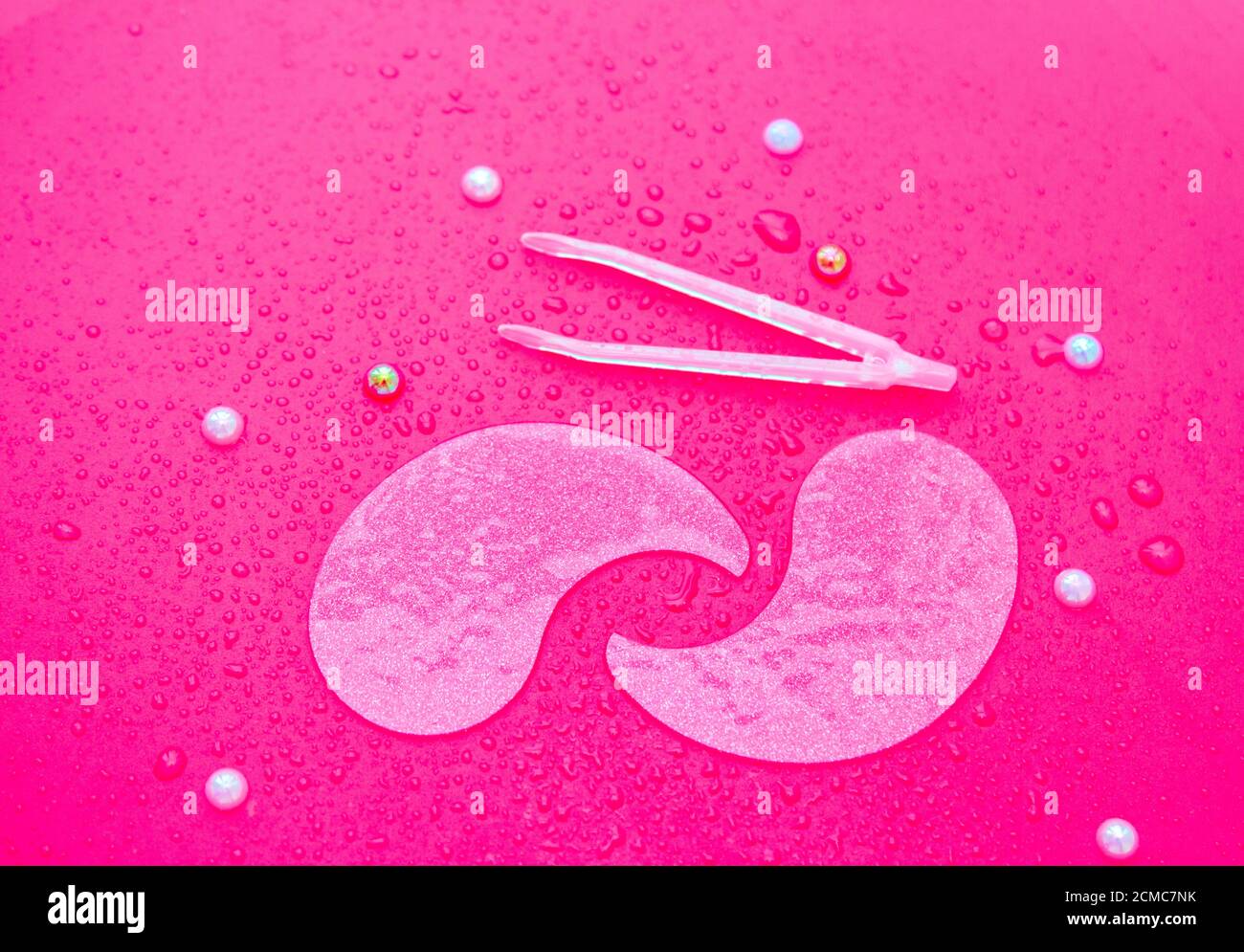 Idrogel cosmetico idratante collagene cerotti oculari su sfondo rosa con gocce d'acqua Foto Stock