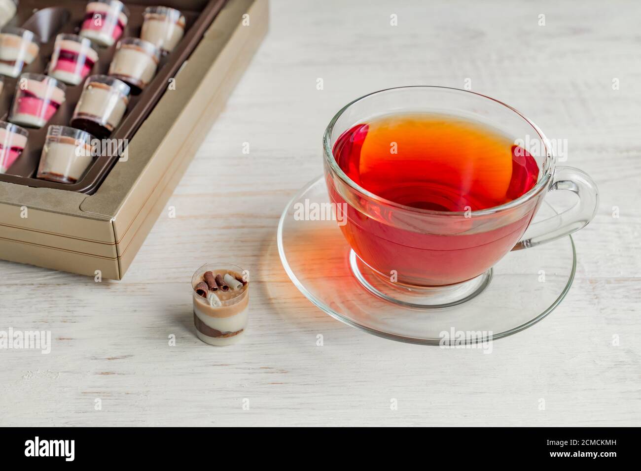 caramelle praline al cioccolato e tazza di tè nero su bianco sfondo di legno Foto Stock