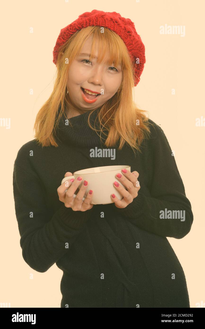 Felice giovane donna asiatica sorridente e azienda tazza da caffè Foto Stock