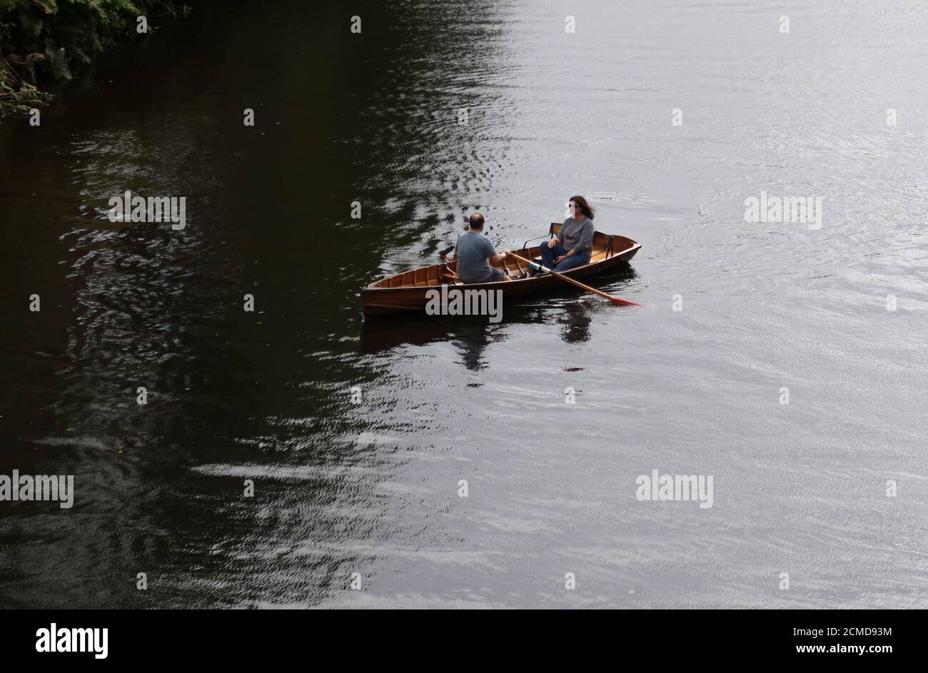 Coppia in barca a remi in legno nel mezzo del fiume Foto Stock