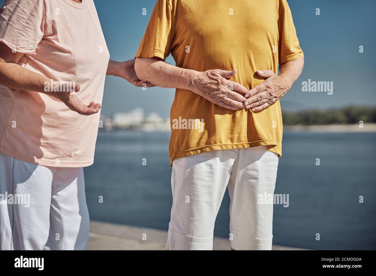 Uomo caucasico anziano che tiene lo stomaco con entrambe le mani Foto Stock