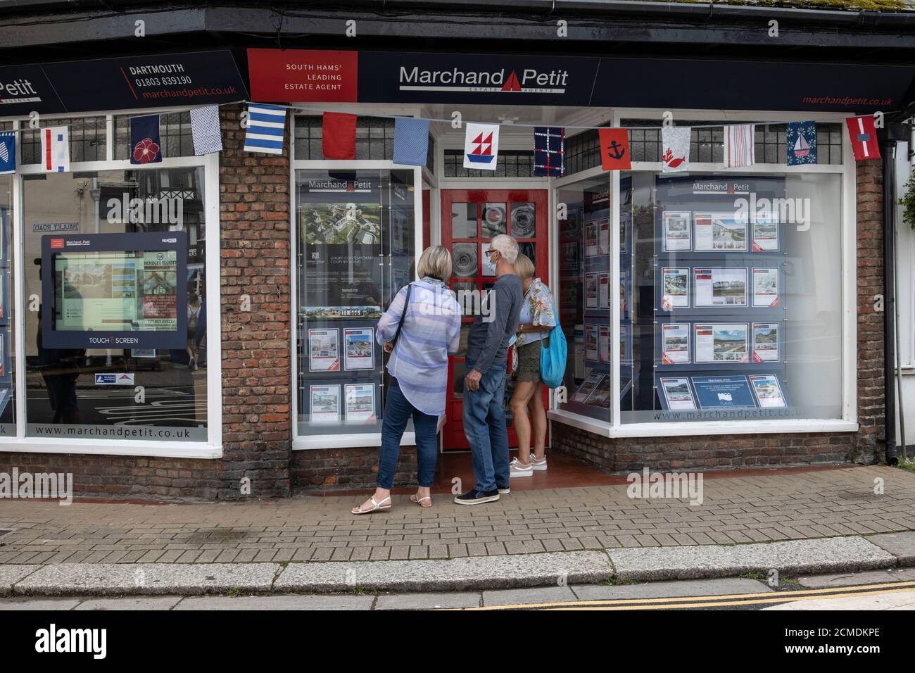 Le famiglie che guardano alle finestre degli Agenti immobiliari mentre sono in vacanza a Dartmouth, South Hams, Devon, Inghilterra, Regno Unito Foto Stock