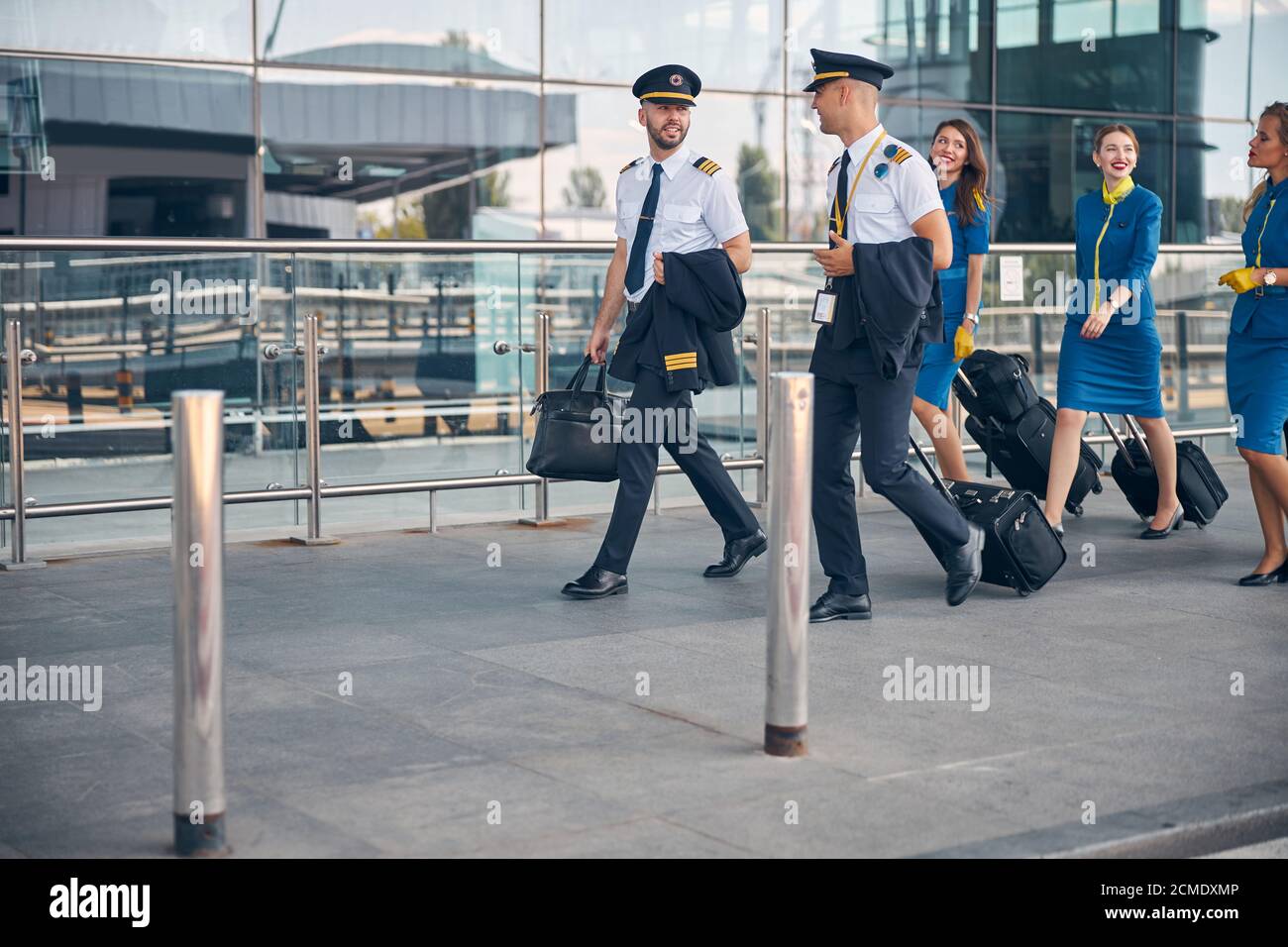 Lavoratori delle compagnie aeree con valigie di viaggio che camminano per strada Foto Stock