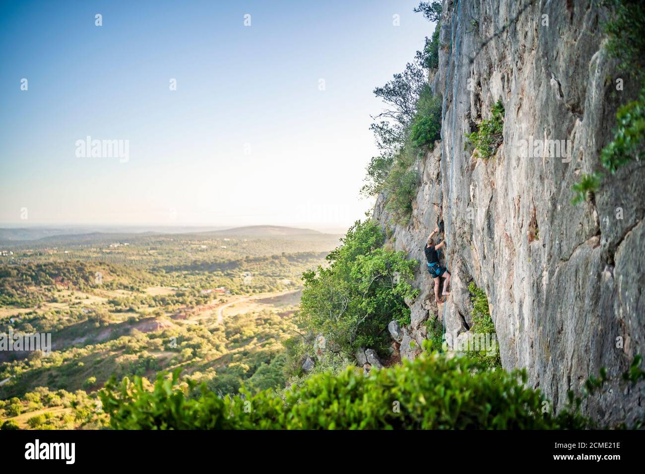 Uomo che arrampica una roccia con attrezzatura in Portogallo Foto Stock