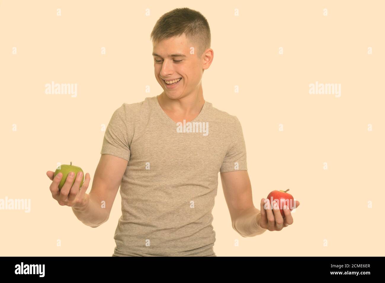 Felice giovane uomo caucasico sorridere mentre scegliendo tra rosso e verde mela Foto Stock