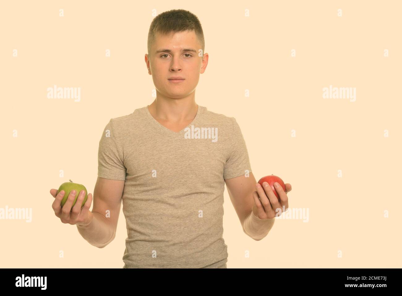 Giovane uomo caucasico holding rosso e verde mela Foto Stock