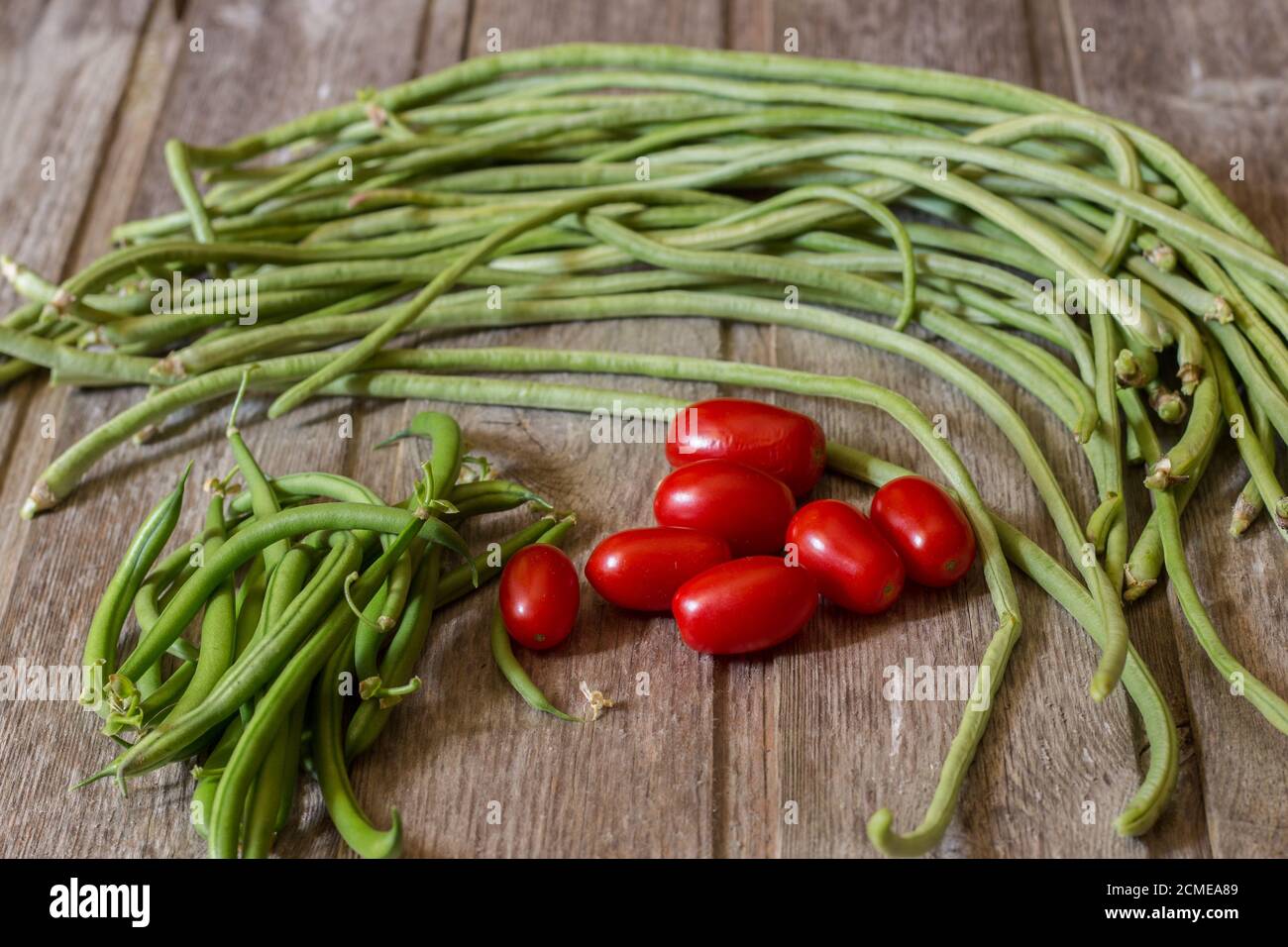 Fagioli verdi con pomodori ciliegini su fondo di legno Foto Stock