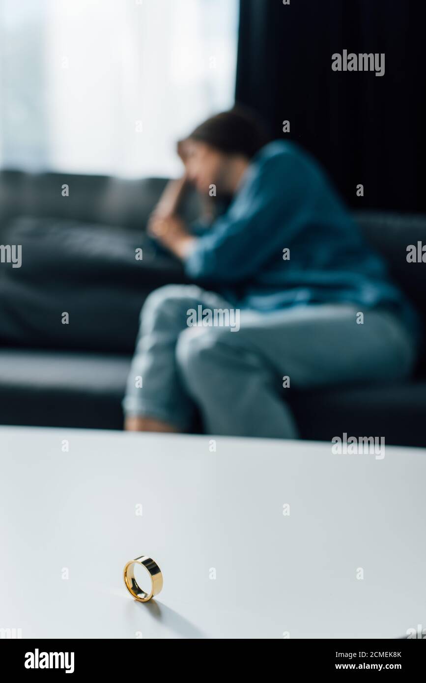 fuoco selettivo dell'anello d'oro sulla tabella del caffè vicino alla donna, concetto di divorzio Foto Stock