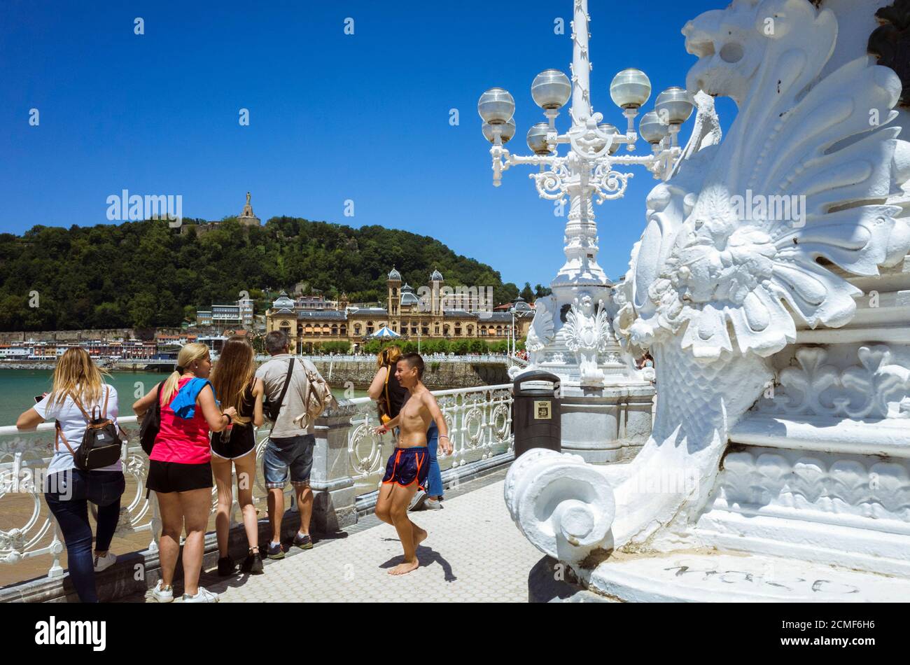 Donostia, Gipuzkoa, Paesi Baschi, Spagna - 12 luglio 2019 : primo piano di lampada da strada ornata e la gente che guarda alla collina Urgull e il municipio in b Foto Stock