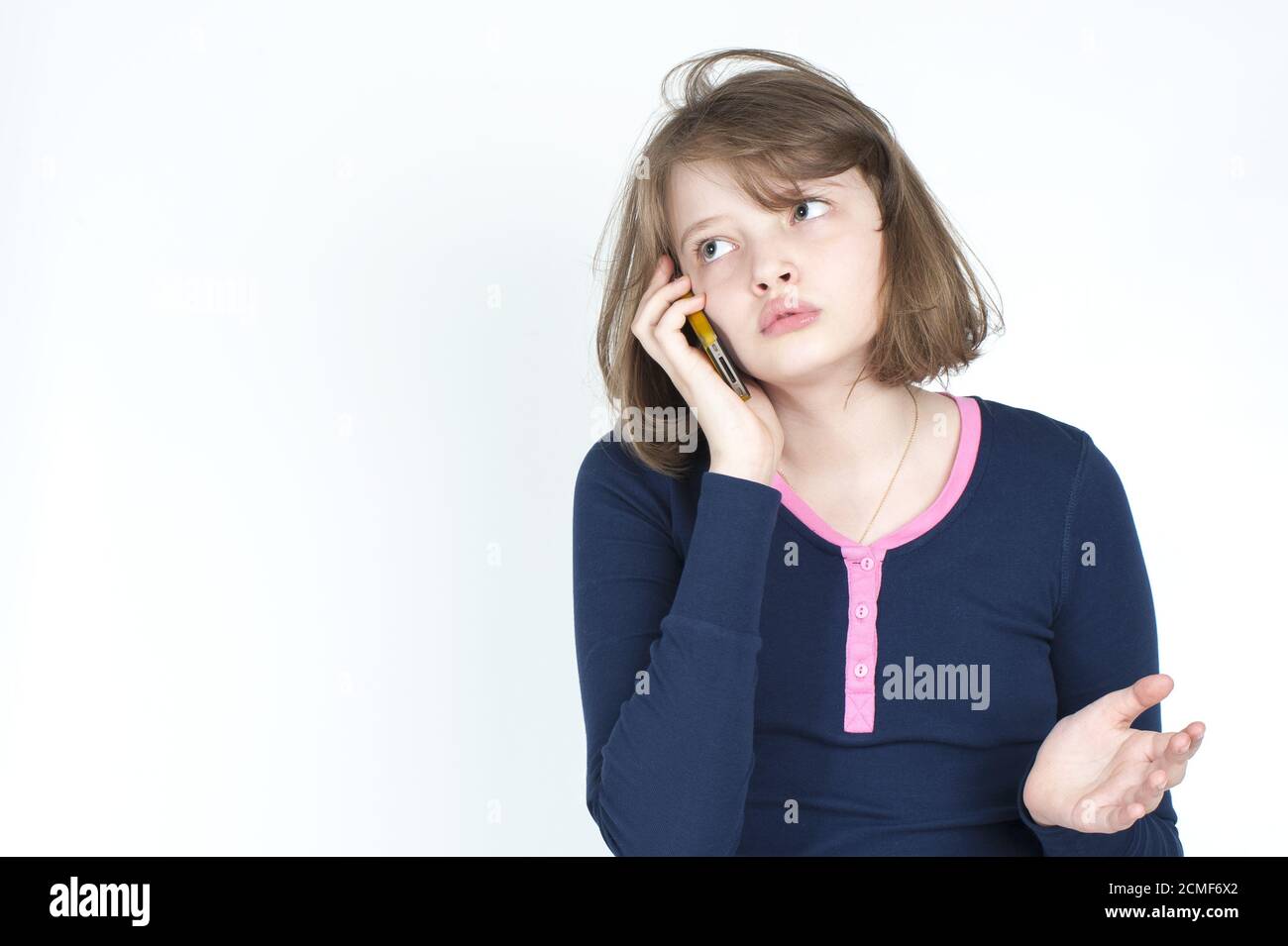 Piccola ragazza emotiva che parla sul telefono cellulare. Foto Stock