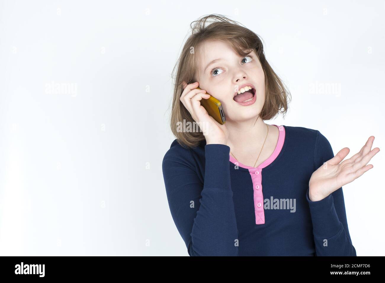 Piccola ragazza emotiva che parla sul telefono cellulare. Foto Stock