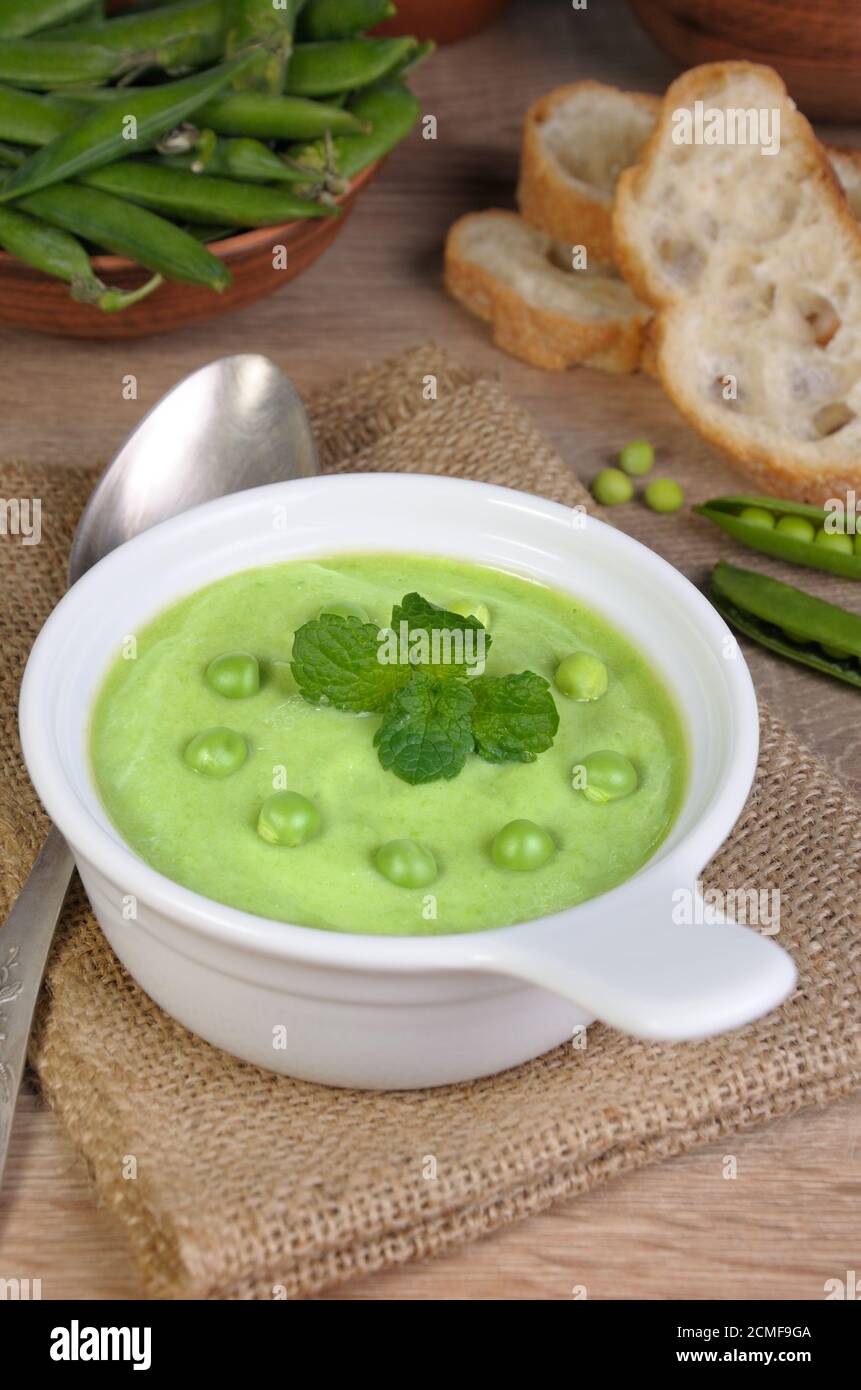 Un piatto di zuppa di purea di piselli verdi con menta su un tavolo Foto Stock