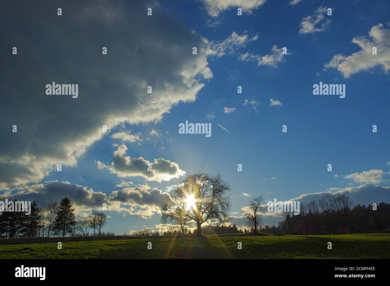 Incredibile tramonto su un verde scuro paesaggio di campagna delle colline ondulate con raggi di sole Foto Stock