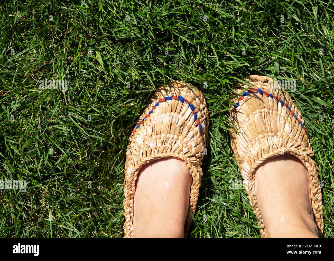 Le gambe delle donne sono vestite con un paio di vecchie scarpe in ghisa in piedi sull'erba. Foto Stock