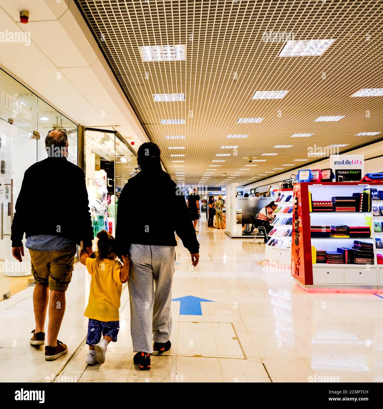 Anonimo uomo e donna camminare in UN centro commerciale con il loro bambino, tenendo le mani Foto Stock