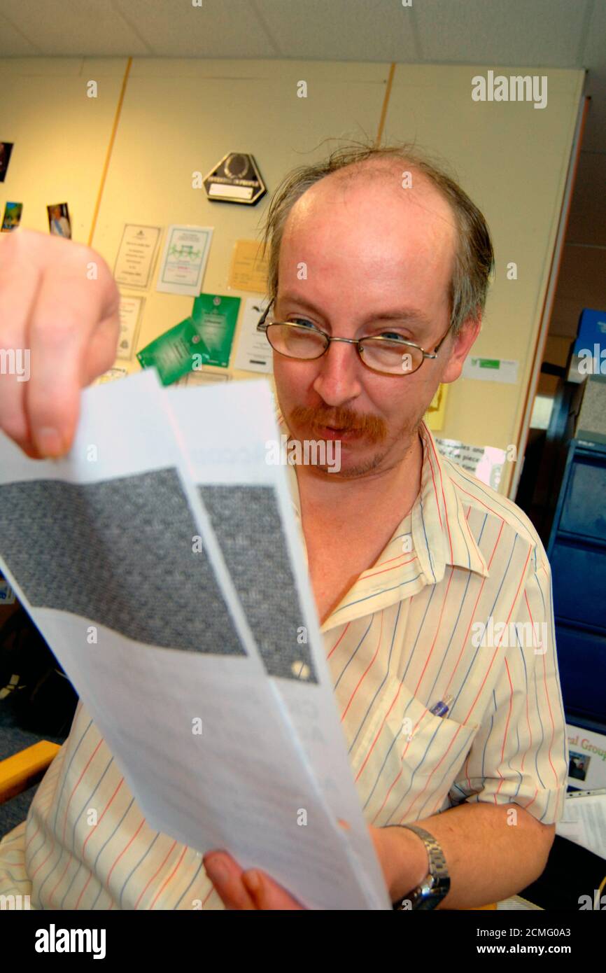 Uomo con disabilità di apprendimento che legge grande stampa dichiarazione bancaria; centro di comunità; Bradford; Yorkshire UK Foto Stock