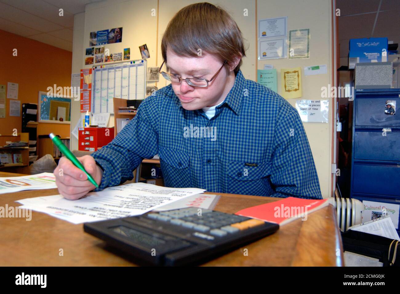 Giovane con disabilità di apprendimento che legge grande stampa dichiarazione bancaria; centro di comunità; Bradford; Yorkshire UK Foto Stock