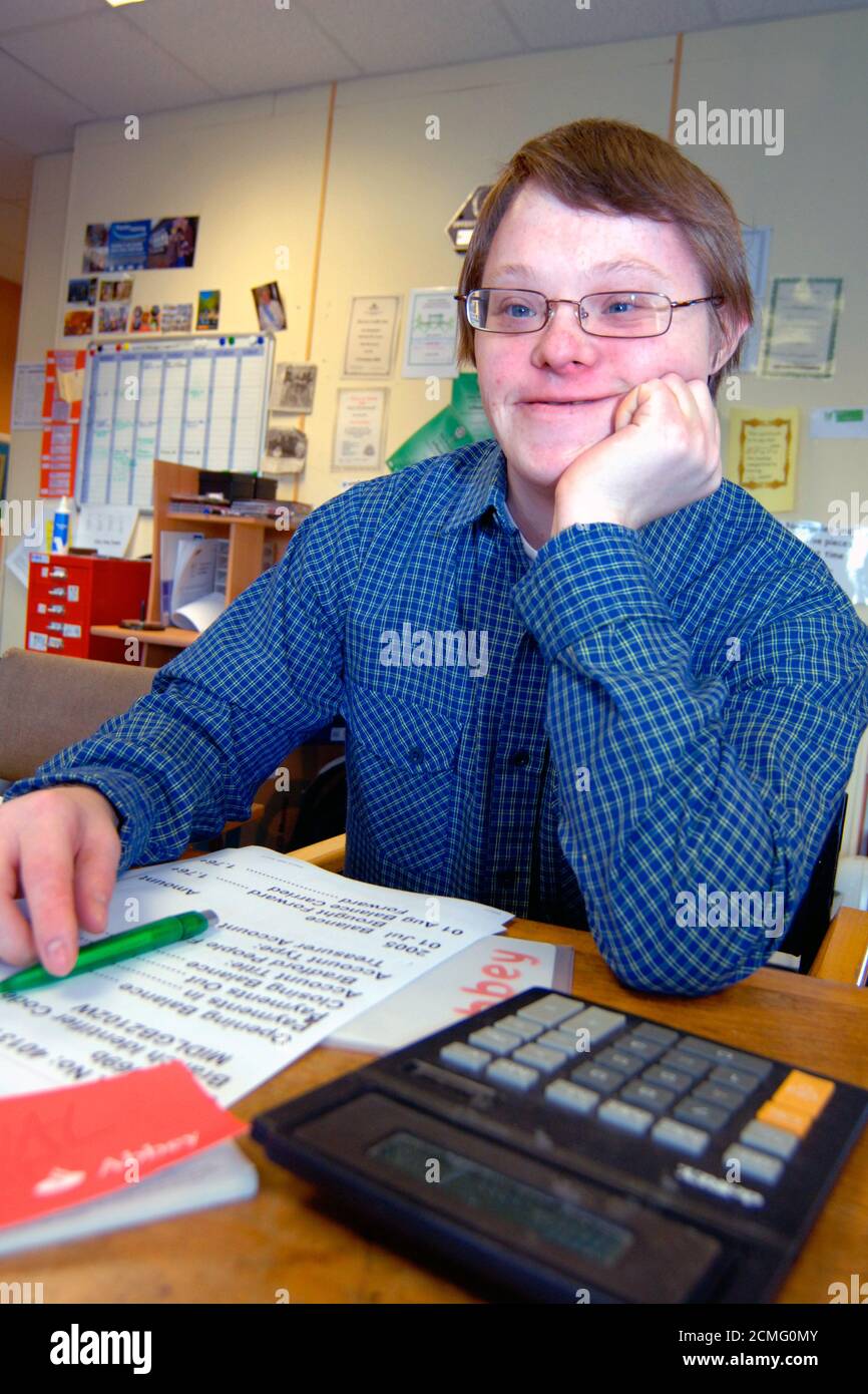 Giovane con disabilità di apprendimento che legge grande stampa dichiarazione bancaria; centro di comunità; Bradford; Yorkshire UK Foto Stock