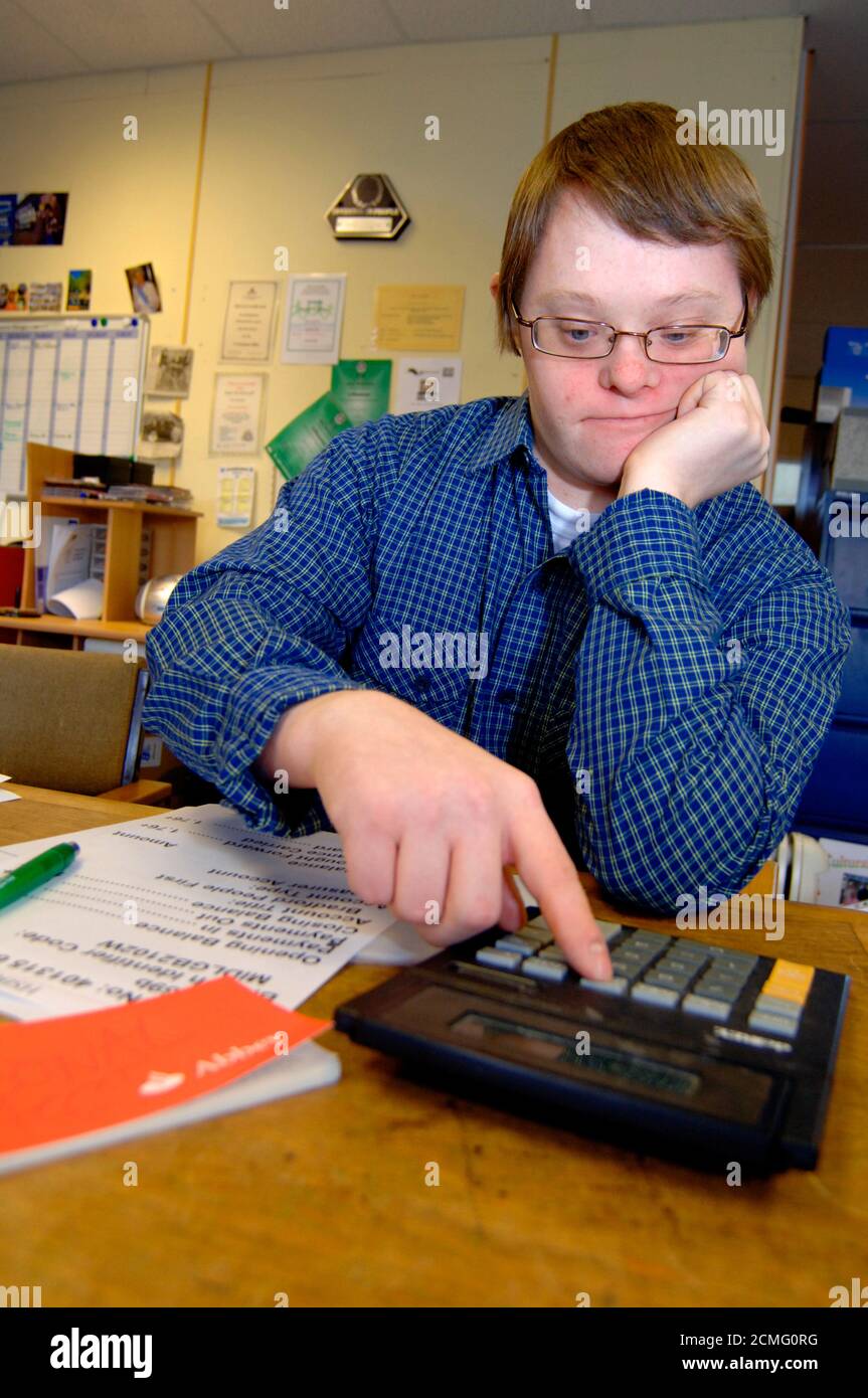 Giovane con disabilità di apprendimento che legge grande stampa dichiarazione bancaria; centro di comunità; Bradford; Yorkshire UK Foto Stock