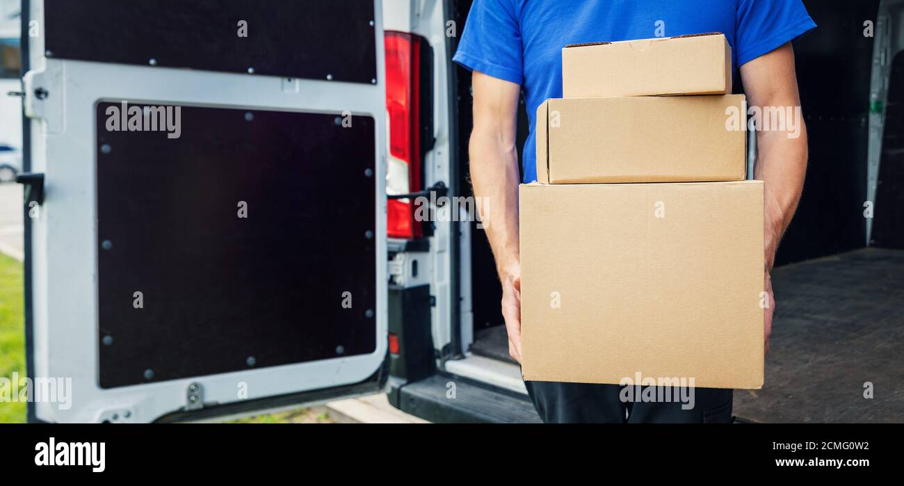 addetto alla consegna che tiene una pila di scatole davanti sullo sfondo del furgone. spazio per la copia Foto Stock