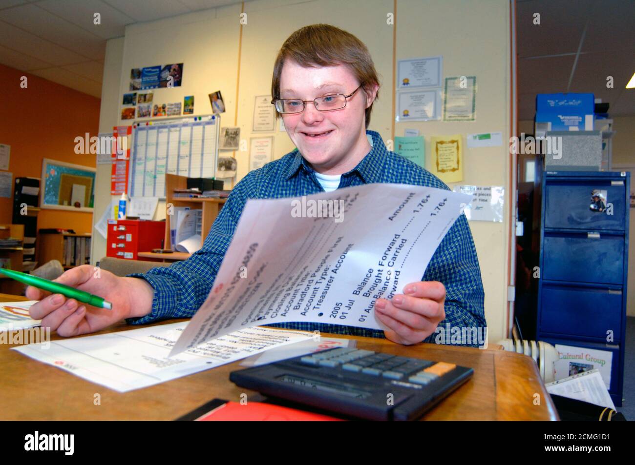 Giovane con disabilità di apprendimento che legge grande stampa dichiarazione bancaria; centro di comunità; Bradford; Yorkshire UK Foto Stock