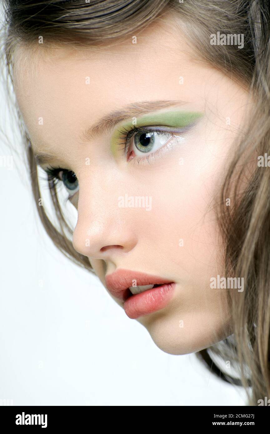 Il volto di una giovane ragazza con trucco luminoso sugli occhi. Foto Stock