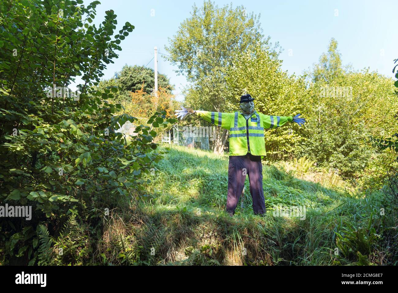 Vita dimensione insolito vista sulla corsia di paese vestito polizia scarecrow ufficiale che indossa un'uniforme intelligente nella vista alta del giardino anteriore giacca di polizia Foto Stock