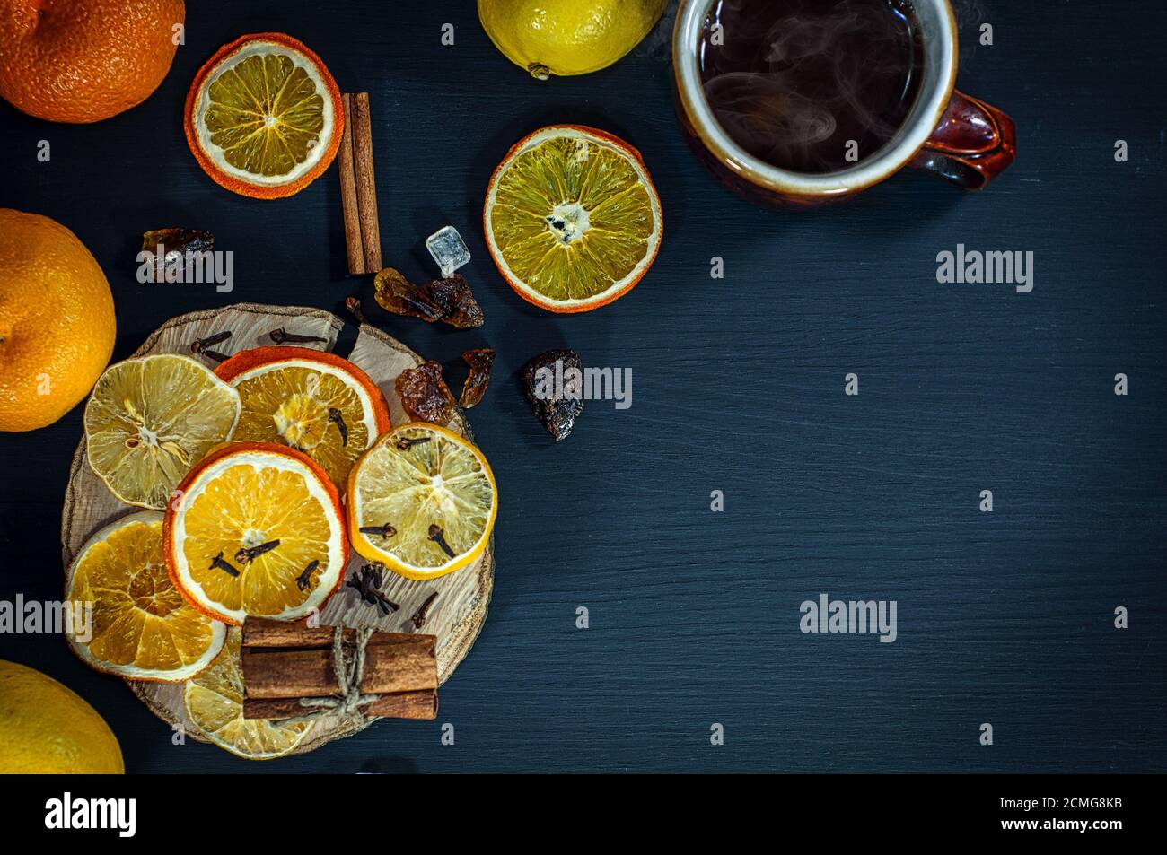 Tè nero caldo con pezzi di frutta e spezie una superficie di legno nero Foto Stock