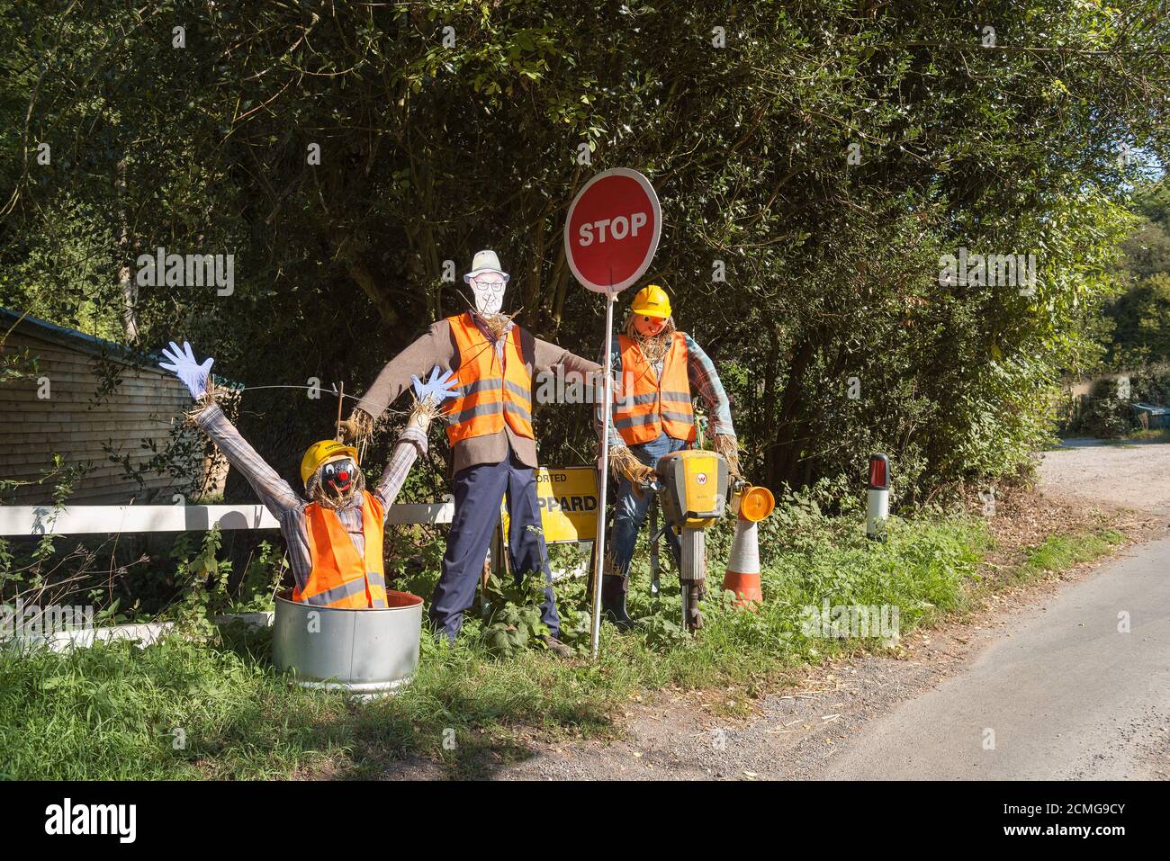 Vista insolita a grandezza naturale sulla corsia di campagna vestita 3 falco da lavoro in piedi che indossa un'uniforme intelligente nel giardino di fronte con stop segno e una sorpresa Foto Stock