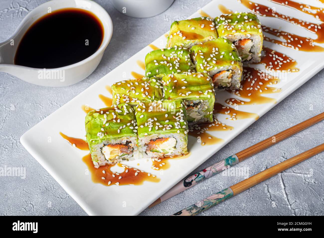 Sushi Imposta nigiri, Uramaki, California, Philadelphia, su un piatto bianco. Zenzero e wasabi nelle vicinanze. Salsa di soia in un recipiente bianco. Su uno sfondo grigio chiaro Foto Stock