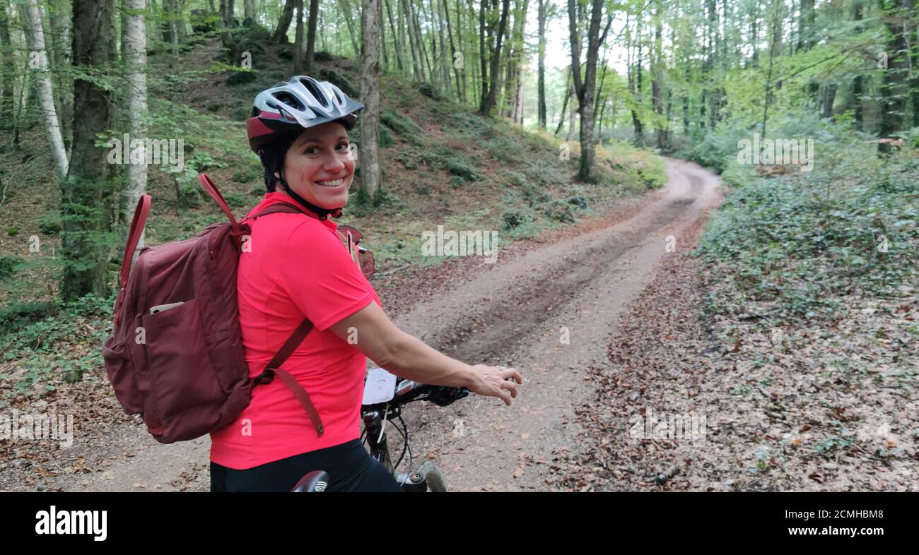 donna in bicicletta in una foresta con alberi verdi Foto Stock