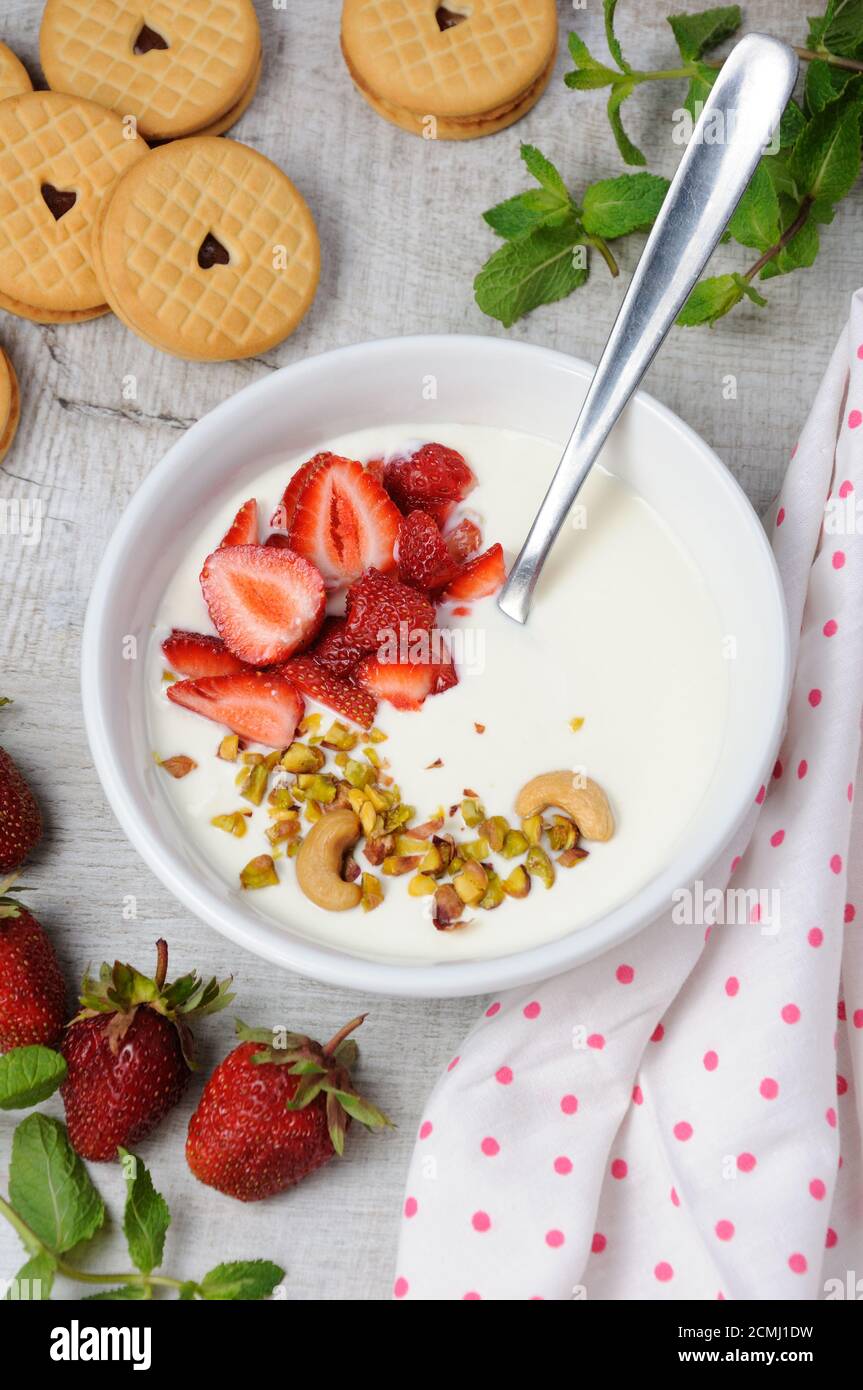 Zuppa di latte alle farfalle ghiacciata di yogurt greco con fragole e pistacchi, anacardi. Servire con i cris Foto Stock