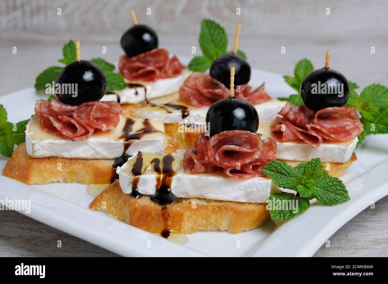 Snack da una fetta tostata di baguette con morbido sotto una muffa bianca nobile Brie formaggio, salame, un berbero Foto Stock