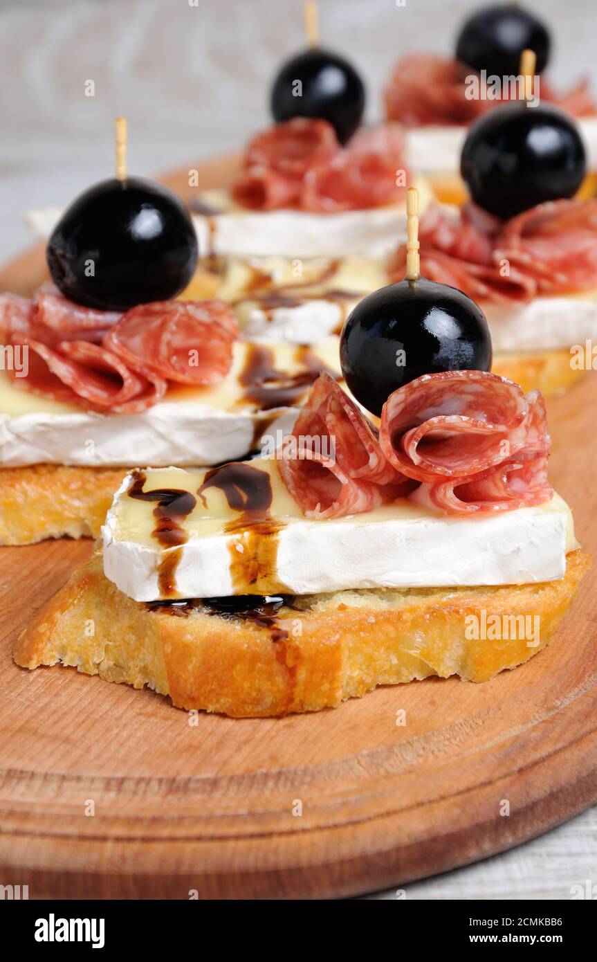Snack da una fetta tostata di baguette con morbido sotto una muffa bianca nobile Brie formaggio, salame, un berbero Foto Stock
