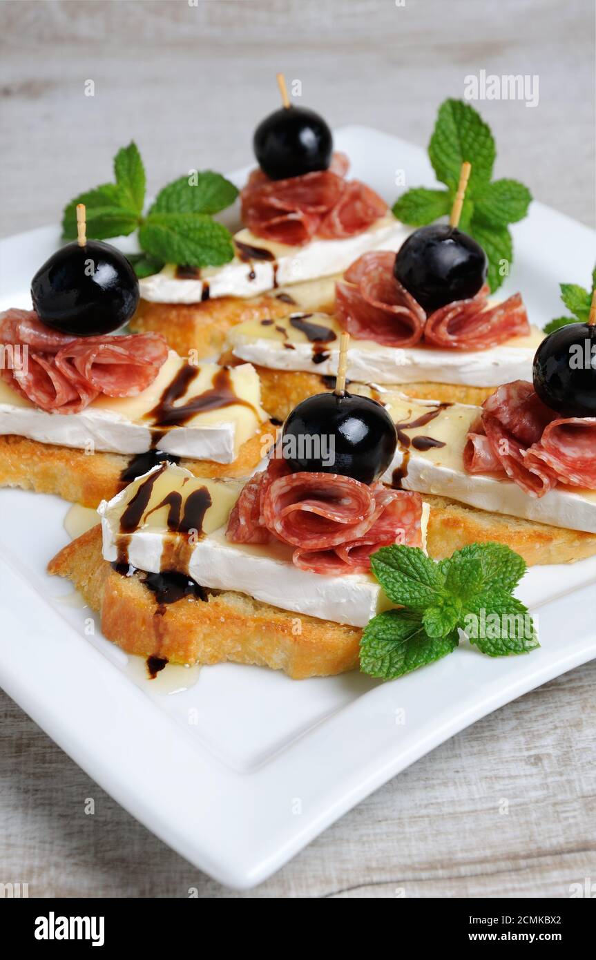 Snack da una fetta tostata di baguette con morbido sotto una muffa bianca nobile Brie formaggio, salame, un berbero Foto Stock