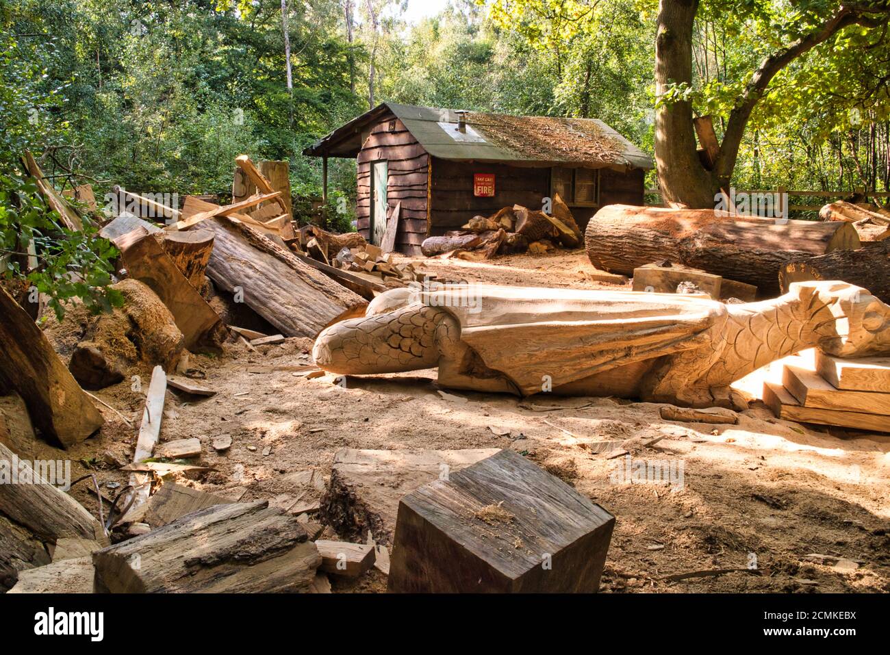 Una capanna di Carvers di legno in una radura di foresta con un hanno scolpito il tronco a forma di drago Foto Stock