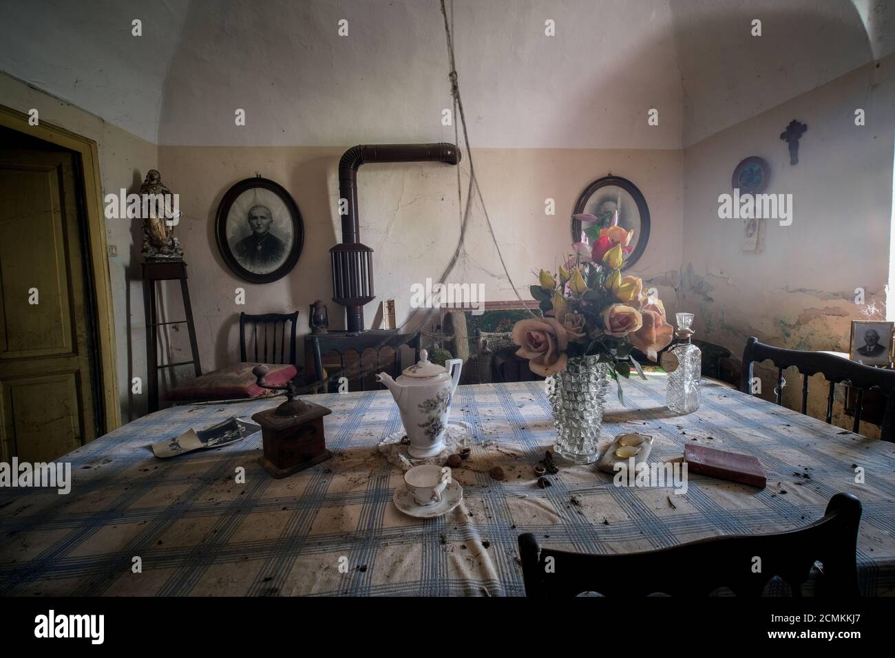 cucina con tavolo e piatti in casa vecchia abbandonata con polvere e ciottoli. Foto di alta qualità Foto Stock