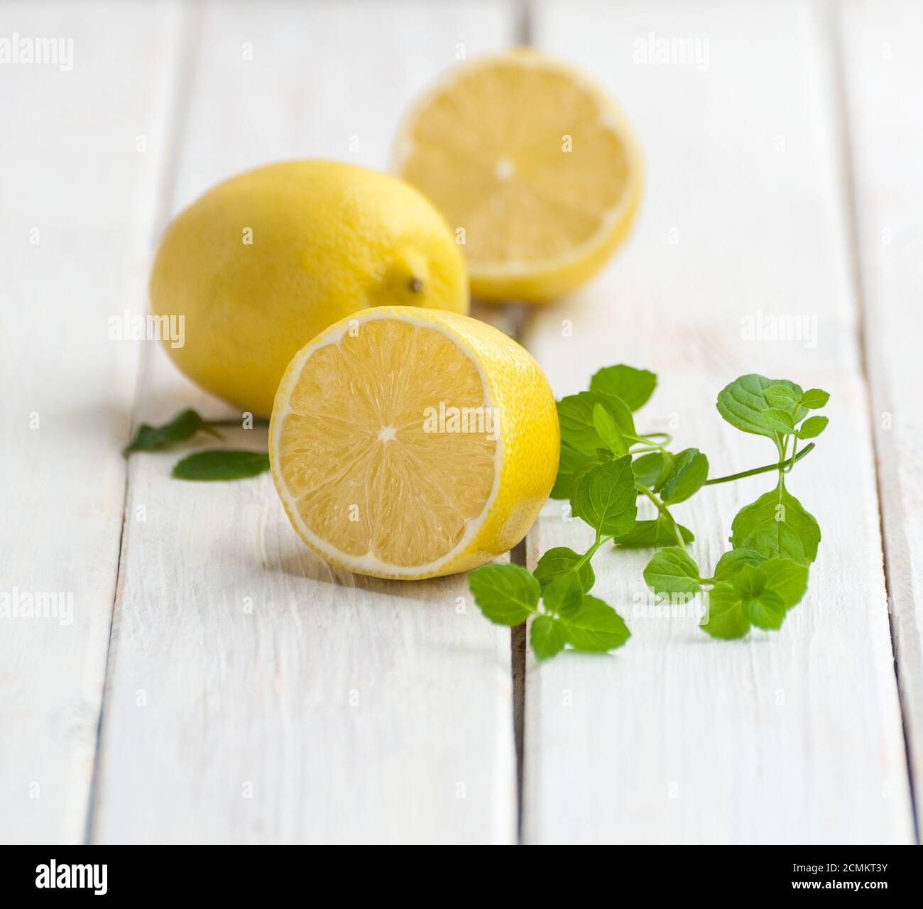 Limoni maturi e un ramo di menta su un tavolo di legno bianco. Foto Stock