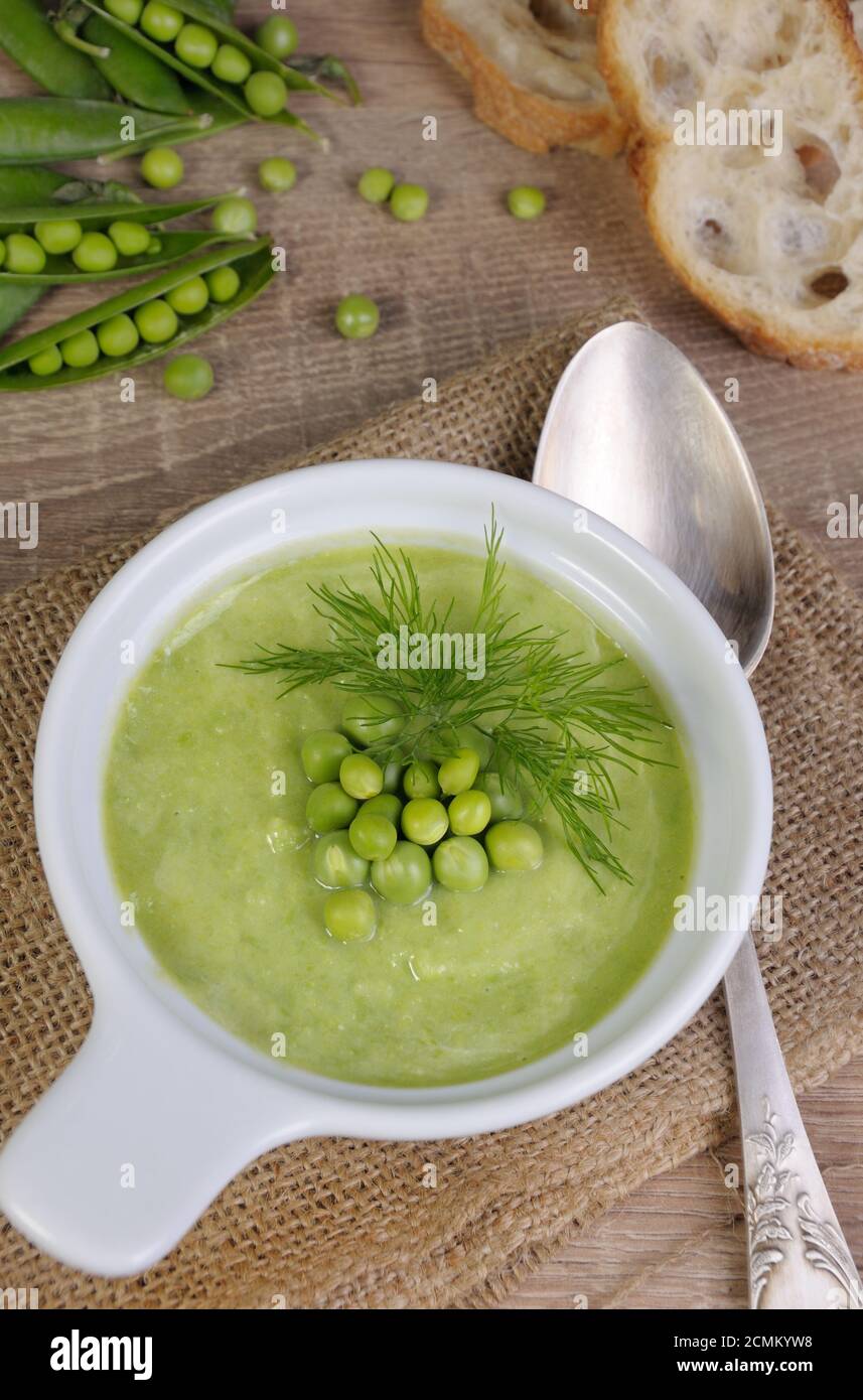 Un piatto di zuppa di purea di piselli verdi con aneto su un tavolo Foto Stock