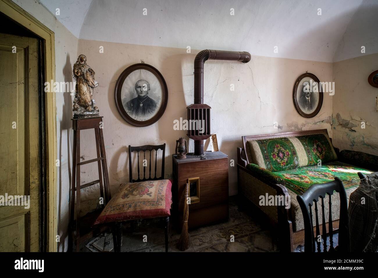 camera da letto con stufa a legna in una vecchia casa abbandonata con polvere e ciottoli. Foto di alta qualità Foto Stock