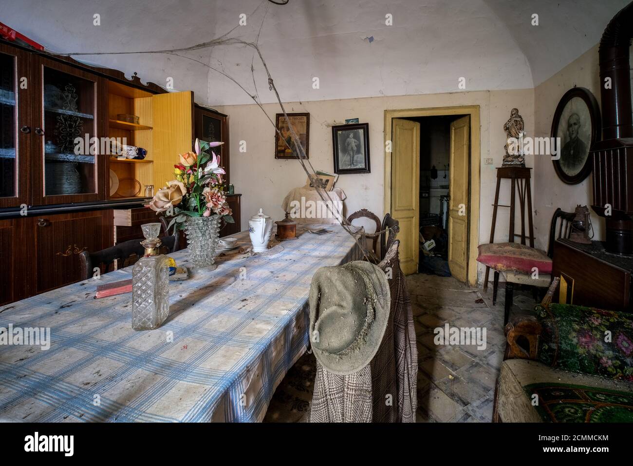 cucina con tavolo e piatti in casa vecchia abbandonata con polvere e ciottoli. Foto di alta qualità Foto Stock