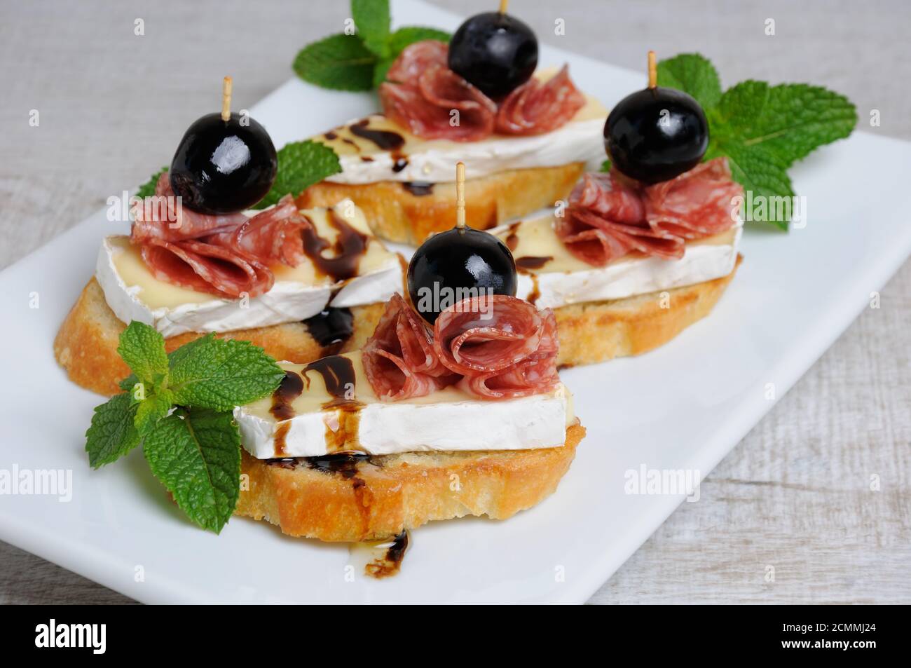 Snack da una fetta tostata di baguette con morbido sotto una muffa bianca nobile Brie formaggio, salame, un berbero Foto Stock