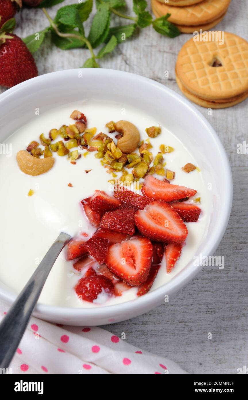 Zuppa di latte alle farfalle ghiacciata di yogurt greco con fragole e pistacchi, anacardi. Servire con i cris Foto Stock